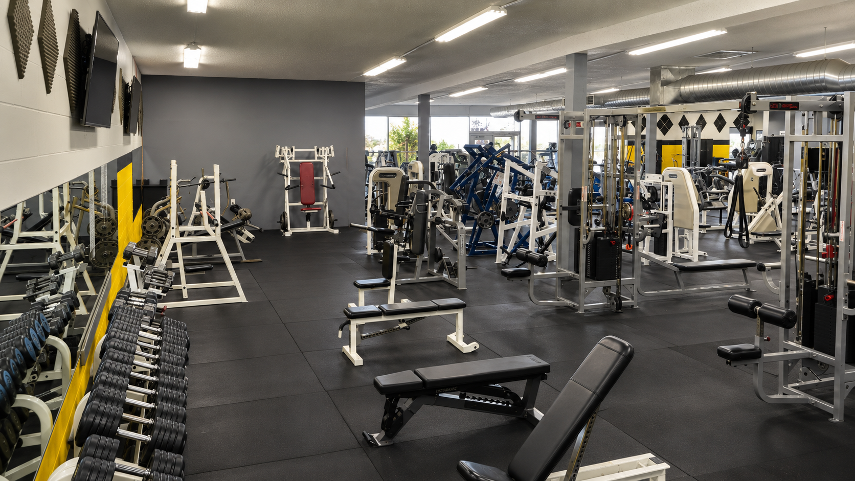 Open lifting floor with dumbbells, benches, and machines at Madtown Fitness